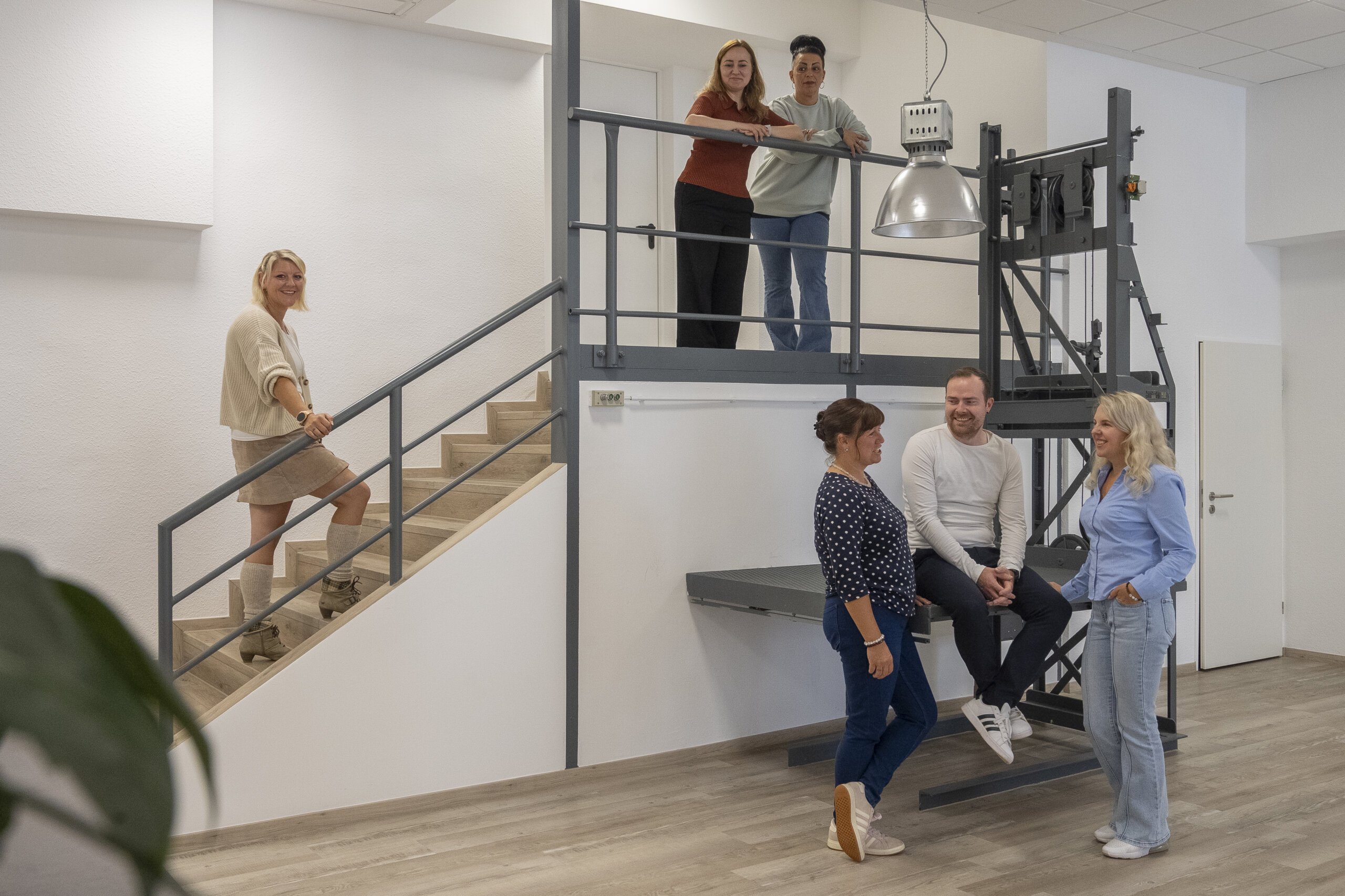 Das Pflege-Wessel-Team im Gespräch an Treppe und ehemaligem Lastenaufzug.